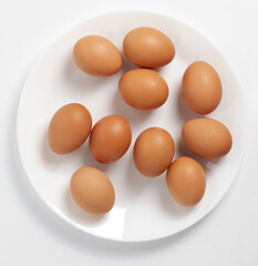Composition Brown eggs on a plate. White background. Top view