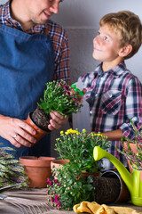 Child helps to father planting flowers. Family time at home