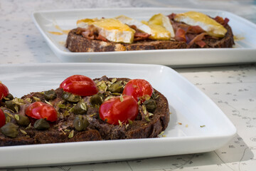 Delicious Italian bruschetta with toasted bread and with cherry tomatoes, basil and garlic and toasted bread with fresh cheese, honey and bacon