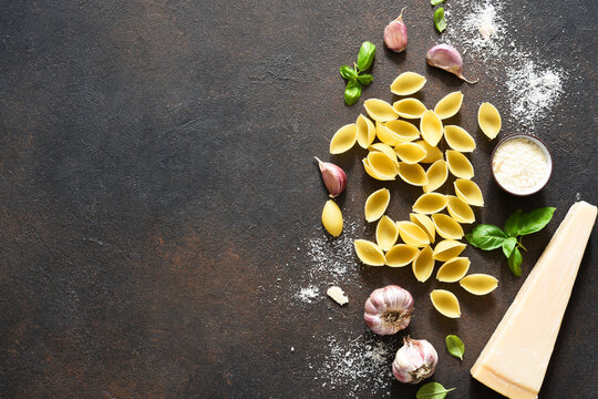 Raw Shell Pasta With Parmesan, Olive Oil And Basil On A Concrete Background. View From Above. Ingredients For Making Pasta.