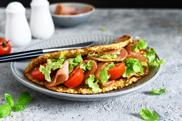 Pancake with ham, salad and tomatoes on a concrete gray background. Breakfast on the kitchen table.