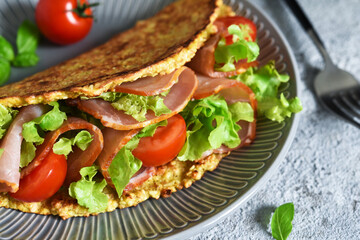 Pancake with ham, salad and tomatoes on a concrete gray background. Breakfast on the kitchen table.