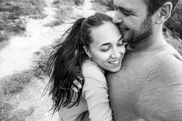 Black and white selfie photo of a happy couple in love. A man and a woman hug with their eyes closed and laugh.