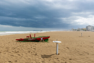 Fototapeta premium A typical red wooden rescue boat on the beach of Rimini, Italy, during a winter storm