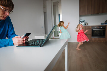 father working remotely while kids dance and have fun