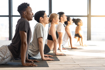 Side View Of Sporty Multiethnic People Practicing Yoga In Cobra Pose