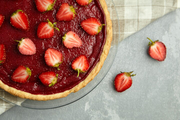 Strawberry tart decorated with fresh berries on linen napkin on grey background