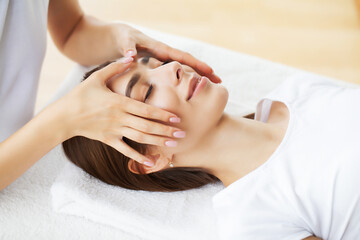 Young woman enjoying of facial massage in spa salon