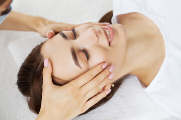 Fototapeta na wymiar Young woman enjoying of facial massage in spa salon