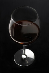 A glass of red wine on a dark background.