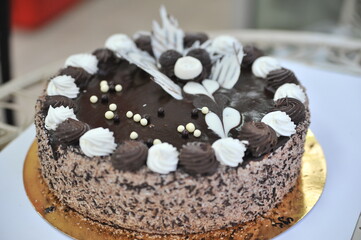 Triple chocolate cake frosted on the sides with hand crafted chocolate frosting decorations on tops.