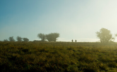 Fototapeta na wymiar Silhouettes of 2 people walking during early morning on Butser Hill, Hampshire.