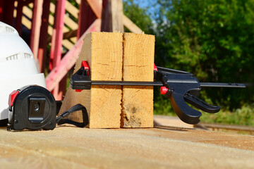 concept of construction of a frame house, a white protective helmet, measuring tape and other tools lie on a wooden table made of boards.