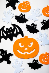 Frame of halloween decoration on pastel white background. Flat lay orange pumpkins, spooky spiders, bat, insects. Top view with copy space. Holiday greeting card mockup.