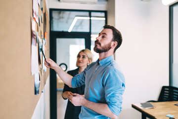 Obraz premium Satisfied businessman working with partner near cork board