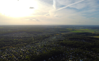 Beautiful top view at sunset on the forest and suburb with houses and a park