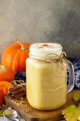Autumn pumpkin spiced latte or coffee in glass with organic ingredients on a light stone countertop. Copy space.