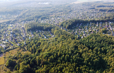 Beautiful top view of suburban cottages with park and forest. Rural landscape with roofs of small houses and villages