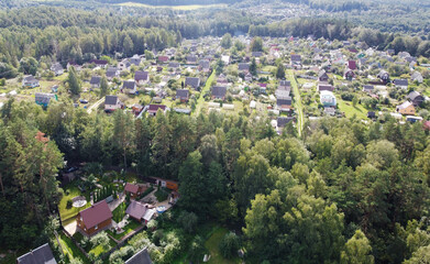 Beautiful top view of suburban cottages with park and forest. Rural landscape with roofs of small houses and villages