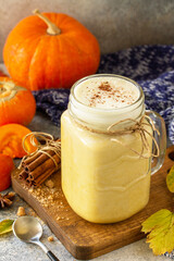Autumn pumpkin spiced latte or coffee in glass with organic ingredients on a light stone countertop.