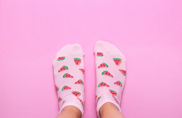 Female feet in colorful socks in watermelon print on a pastel pink background. Top view.Copy space.