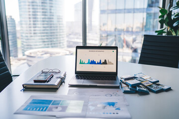 Modern laptop computer with infographic statistics for business displayed on screen staying on...