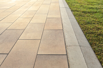 The brown concrete slab sidewalk is separated by a gray curb from the lawn.