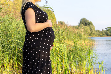 Schwangere Frau an einem See im Sommer
