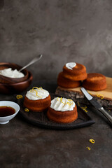Homemade cupcakes with cream cheese on a small ceramic stand. Food photography on dark backgrounds.