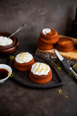Homemade cupcakes with cream cheese on a small ceramic stand. Food photography on dark backgrounds.