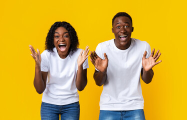 Surprised black couple screaming and raising hands up