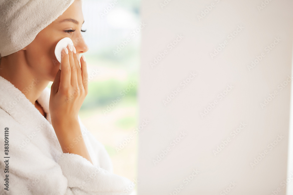 Wall mural beautiful smiling young woman removing makeup with a facial wipe