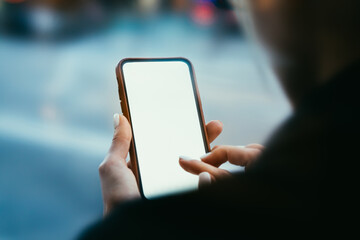 Crop faceless female student surfing internet on smartphone in street
