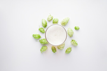 Beer in a glass and hop cones on a white background, flat lay
