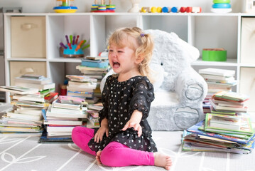 Caucasian cute toddler crying with the books