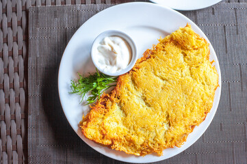 Big potato pancake with sour cream. Deruny on white plate, ukrainian food