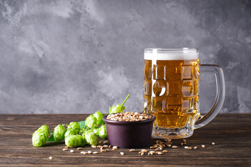 Hops and glass of light beer on wooden background, space for text