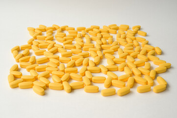 Fototapeta premium pharmacy concept of handful of yellow tablets lying on a white surface