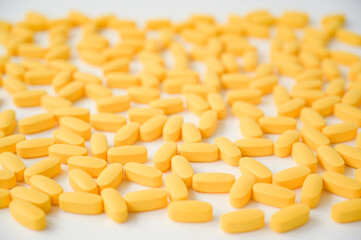 many yellow pills vitamin tablets on white background