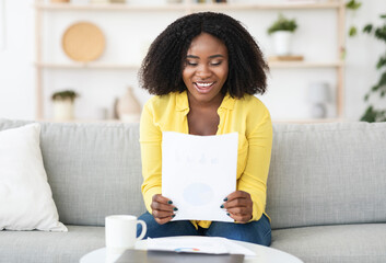 Happy young woman reading good news sitting on couch