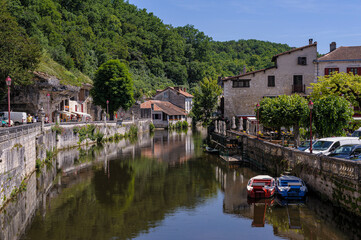 Fototapeta na wymiar In France, in the Périgord, the river crosses the village of Brantome. Houses and trees are reflected in the water.