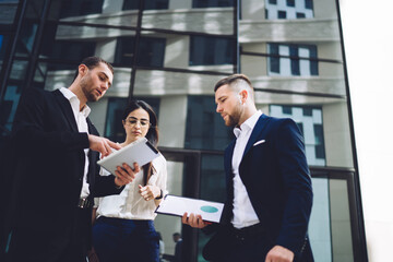 Focused young businesspeople gathering outside and talking about business project