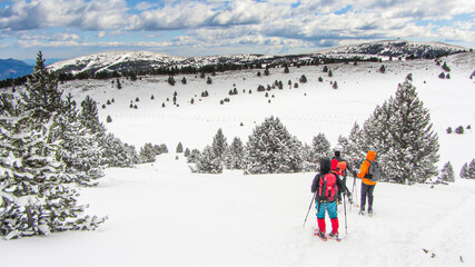 People walking in a snow landscape with snowshoes and backpacks in the Pyrenees. Hiking and skiing in winter.