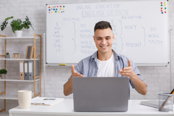 English teacher at home, online practice during COVID-19. Smiling young man rejoices at students...