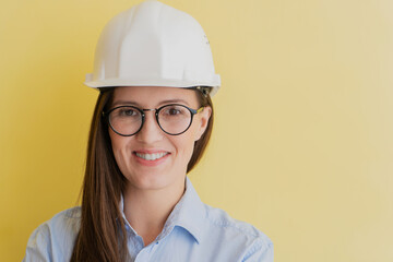 Portrait of smiling beautiful tatar woman engineer in construction helmet and glasses isolated on yellow background