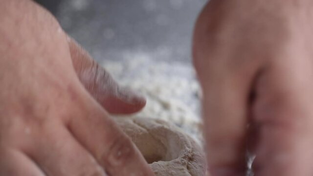 Baker kneads the dough with his fingers, close up