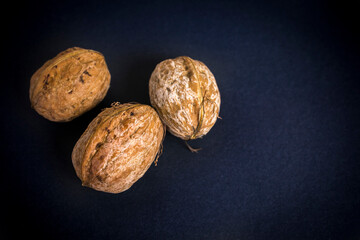 Three walnuts isolated on a black background. Nuts. Healthy food. Closeup.