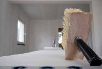 Wide paint brush for glue with wooden base for bristle,black handle,sheet of white wallpaper...