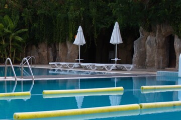 pool with clear water, sun loungers and umbrellas in the relaxation area