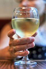 Woman's hand holding a glass of white wine